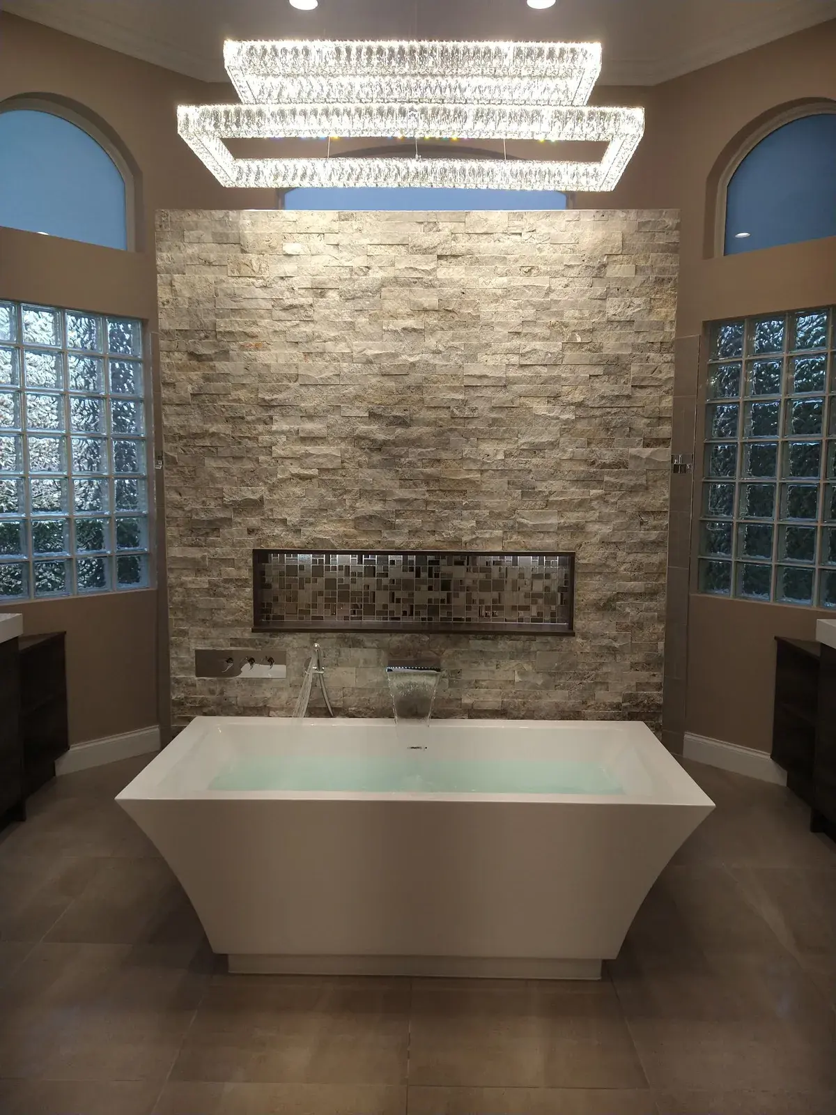 Freestanding soaking tub set against a stone feature wall