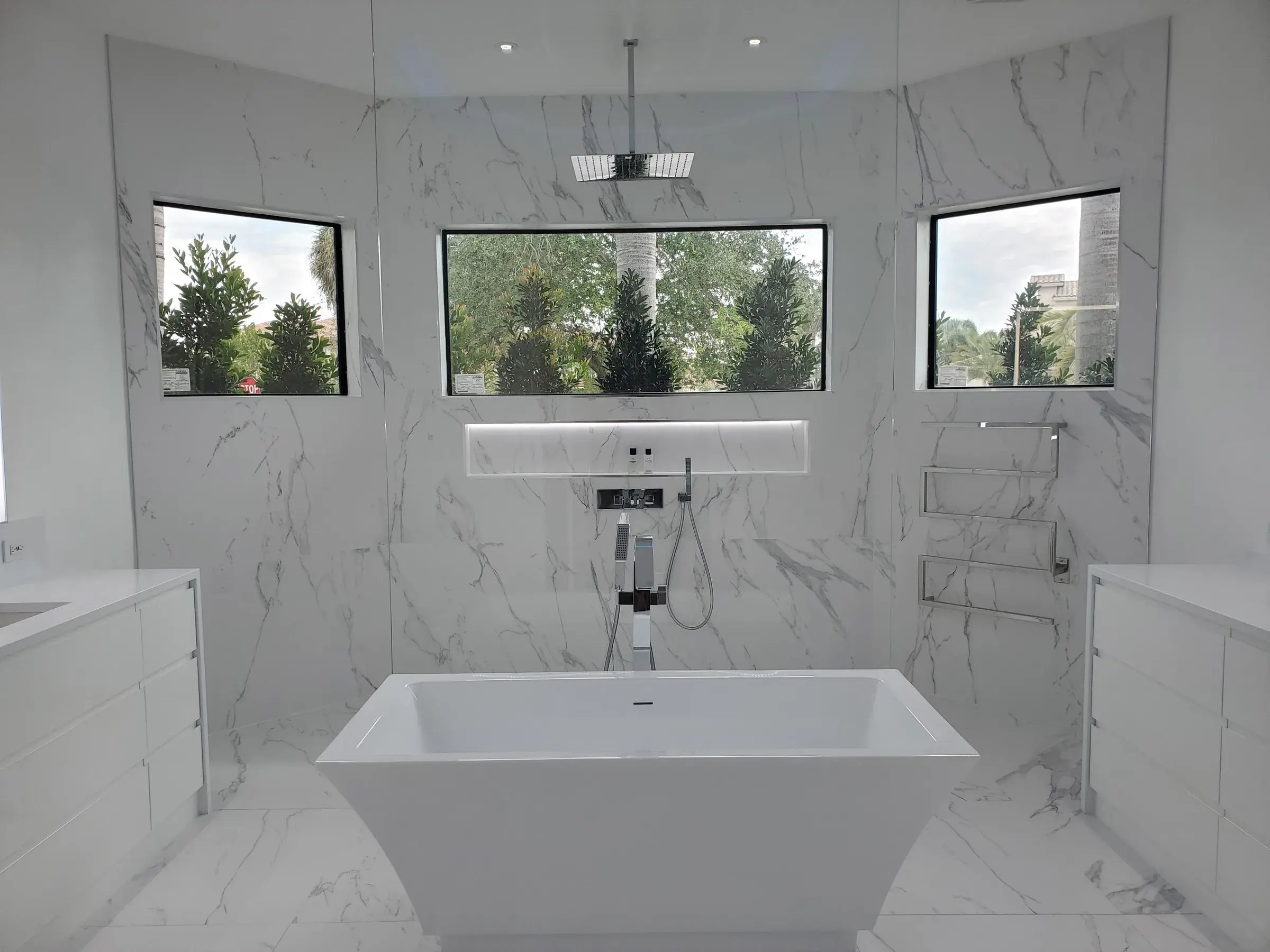 Renovated marble bathroom with freestanding tub and floor-to-ceiling windows